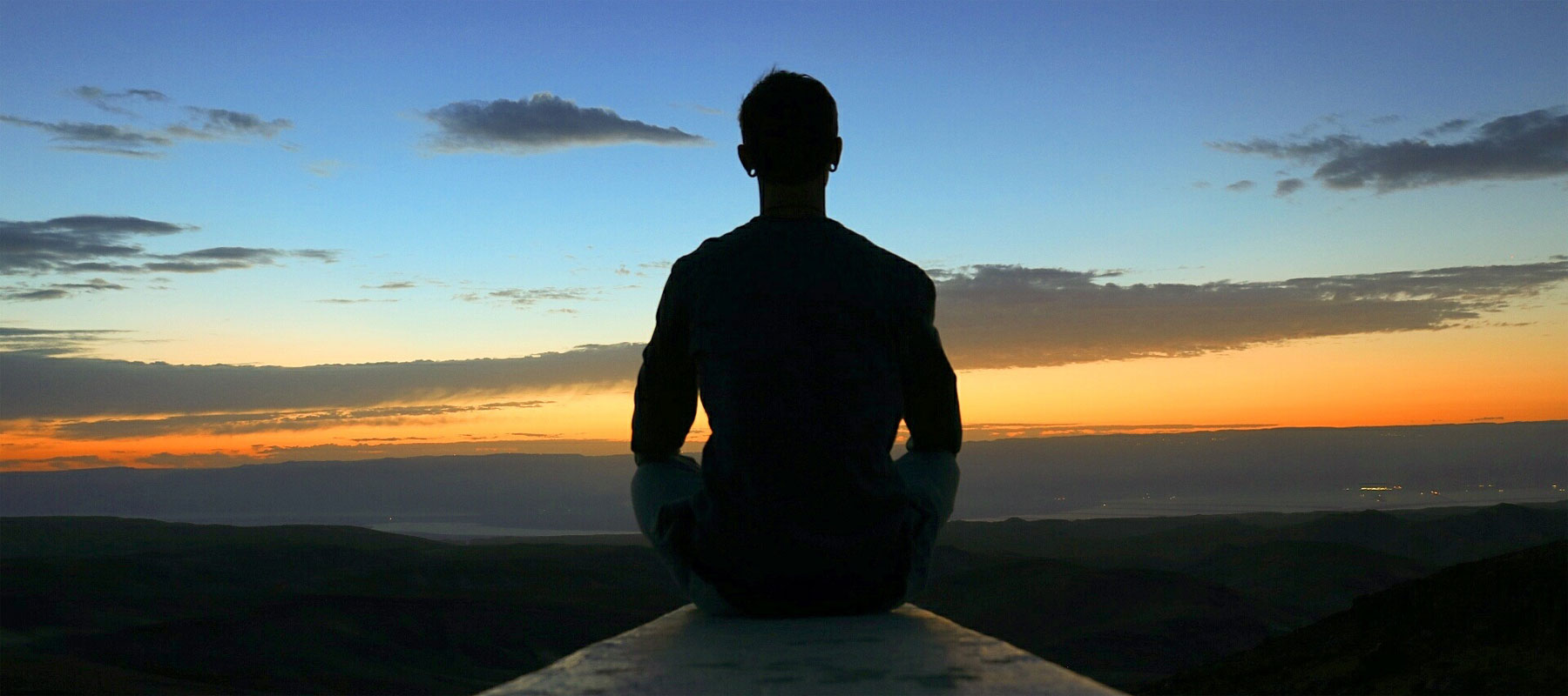 Image of contemplation. Photo of man meditating in nature at sunset.